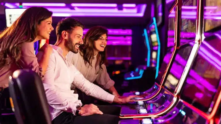 Two women watching a guy play on a slot machine